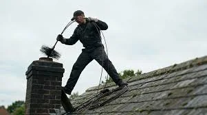 Chimney sweep brushing a rooftop chimney